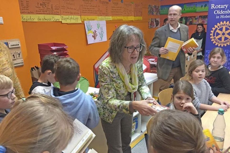 Projektleiterin Susanne Knees und Rotarier Sophus Theophile verteilen Bücher an die 4. Klasse der Grundschule Göhl.