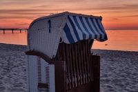 Ines Fedder zeigt, wie malerisch ein Sonnenaufgang in Scharbeutz sein kann – mit Strandkorb und farbenprächtigem Himmel.