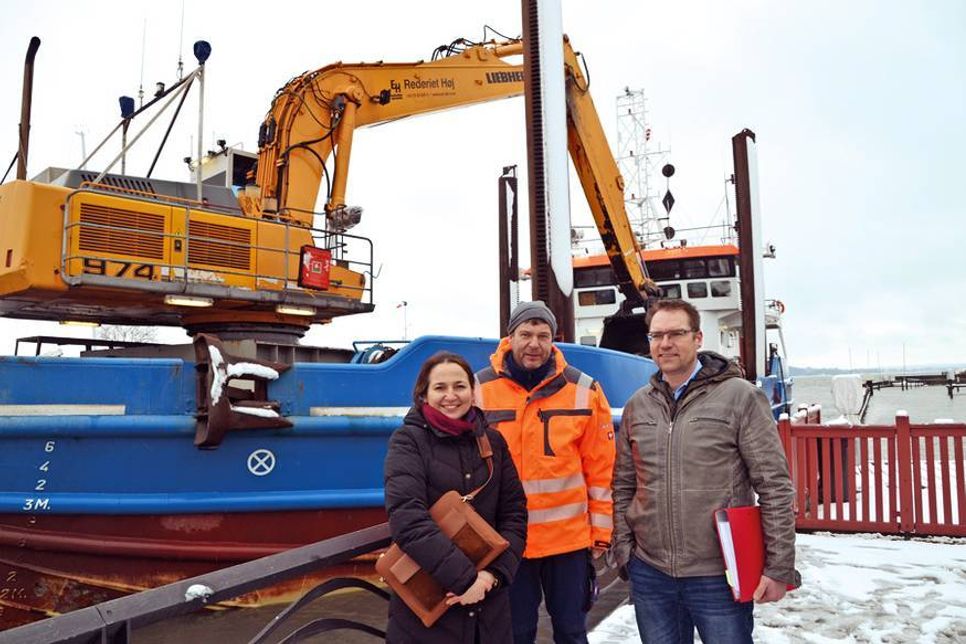 Bürgermeisterin Hatice Kara (von links), Torsten Hauser (Deutsch Dänische Wasserbau GmbH) und Michael Hasselberg, Tiefbau-Ingenieur der Gemeinde Timmendorfer Strand, während der Ausbaggerung vor dem Baggerschiff „Camilla Hof“. (Foto: René Kleinschmidt)