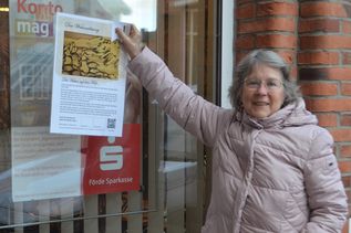 Regina Schultze von der Friedenskirche zeigt bei der Förde Sparkasse schon einmal, wo eines der Plakate zu finden ist.