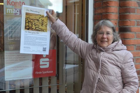 Regina Schultze von der Friedenskirche zeigt bei der Förde Sparkasse schon einmal, wo eines der Plakate zu finden ist.