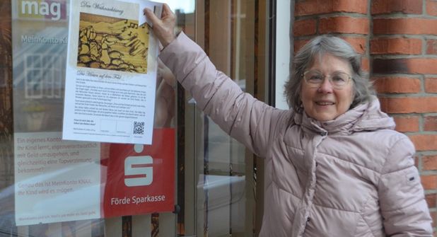 Regina Schultze von der Friedenskirche zeigt bei der Förde Sparkasse schon einmal, wo eines der Plakate zu finden ist.