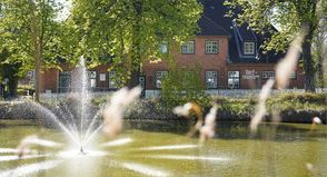 Idyllischer Blick auf Schönwalde: Im Vordergrund der Mühlenteich mit Wasserspiel, dahinter das Dorf- und Schulmuseum in der ehemaligen Dorfschule.