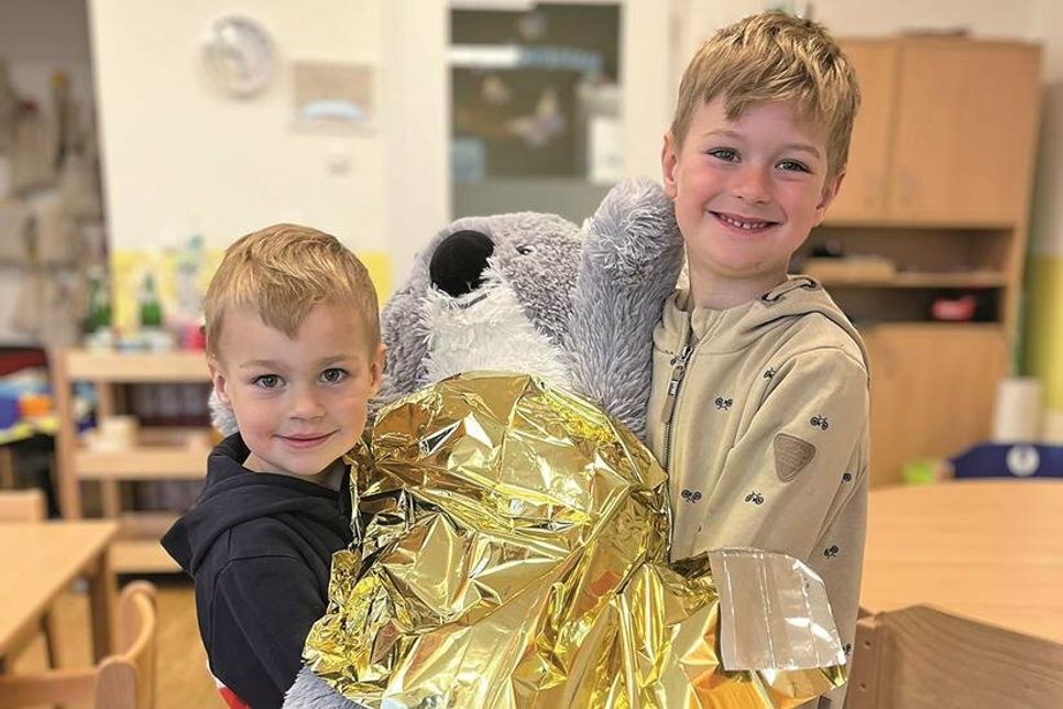 Anton und Levi haben aus dem Dreieckstuch einen Ring angefertigt und üben das Tragen des verletzten Koalabären.