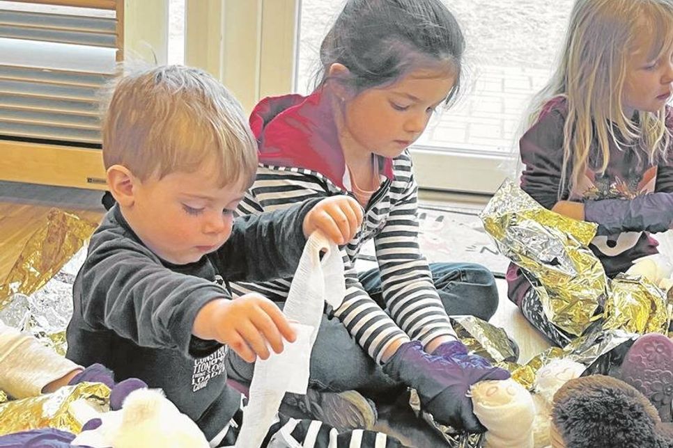 Paul ist zwei Jahre alt und übt fleißig, seinem Teddy einen Verband anzulegen.