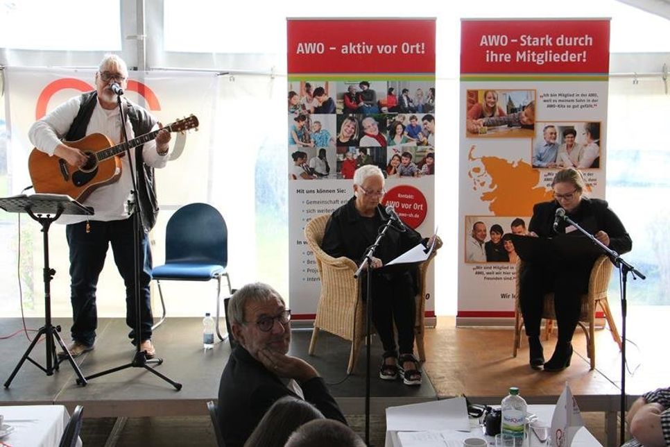 Auf der Bühne trug Gerd Sell aus Kiel Volks- und Arbeiterlieder vor. Dazu gab es eine Lesung zur Geschichte der AWO mit Eike Eckstein von der AWO Kellenhusen und Jessica Prehn vom AWO-Jugendwerk Malente (v. lks.).