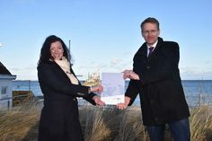 Schleswig-Holsteins Ministerpräsident Daniel Günther überreicht den Förderbescheid an Bettina Schäfer, Bürgermeisterin der Gemeinde Scharbeutz.