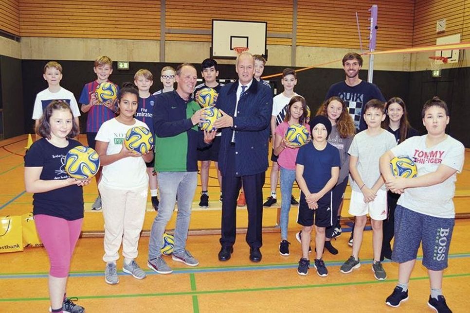 Gemeinsam mit seinem Kollegen Malte Nagursky (r.) und Schülern der Klasse 9d nahm Sportlehrer Jan Claußen die Bälle von Postbank-Gebietsleiter Michael Pöhls entgegen.  (Foto: Setje-Eilers)