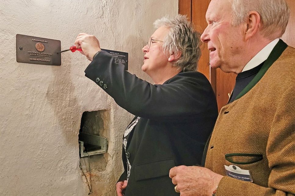 Wolfgang von Ancken als Vertreter der Stiftung Denkmalschutz und Pastorin Anja Haustein zeigen das neue Bronzeschild – Ein Gütesiegel für gelungene denkmalpflegerische Leistung.