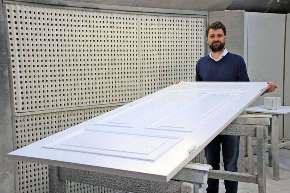 Diplomingenieur für Holztechnik Axel Mielke zeigt ein in der hauseigenen Lackiererei aufgearbeitetes Türblatt eines historischen Hauses.