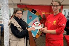 Mona Wiechmann vom eska-Kaufhaus (lks.) und Frederike-Christin Block von der DLRG Neustadt bei der Übergabe der Spende.