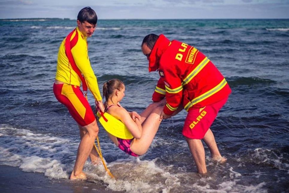 DLRG-Retter bringen eine junge Frau an Land, die beim Schwimmen in Not geraten ist. (Bild: DLRG e.V.)