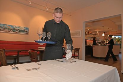 Eindecken für das Menü: Penibel ordnet Kevin Bestecke und Gläser an den Plätzen an – für ein perfektes Bild.