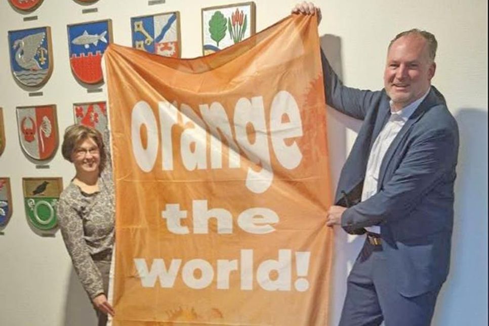 Yvonne Deerberg und Landrat Björn Demmin präsentieren die orangene Fahne der Aktion, die am 25. November in Plön gehisst wird.