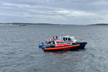 Hand in Hand: Seenotretter und Seenotärzte der DGzRS sowie Beamte der Wasserschutzpolizei versorgen eine Seglerin mit einer Verletzung im Nackenbereich vor Schilksee.