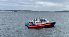 Hand in Hand: Seenotretter und Seenotärzte der DGzRS sowie Beamte der Wasserschutzpolizei versorgen eine Seglerin mit einer Verletzung im Nackenbereich vor Schilksee.