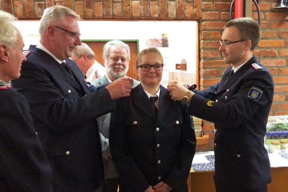 Tanja Jaquet erhält nach ihrer Beförderung zur Feuerwehrfrau neue Schulterklappen von Gemeindewehrführer Kai-Wilhelm Garken und Ortswehrführer Torben Kurth.