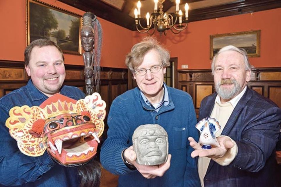 Die Initiatoren der neuen Ausstellung Axel Langfeldt und Volker Liebig (r.) vom Preetzer Heimatverein sowie der Leiter des Lübecker Völkerkundemuseums Dr. Lars Frühsorge (l.) präsentieren eine Auswahl ihrer Reiseandenken: Maske und Zauberstab als rituelles Zubehör von Bali, ein steinerner Olmeken-Kopf aus Mexiko sowie ein Porzellan-Pfau aus der UdSSR, den Volker Liebig 1976 von einer Reise ins damalige Leningrad (St. Petersburg) als typisches Touristenmitbringsel mitgebracht hat. Foto: Schneider