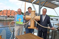 Pastor und Projektmanager Michael Franke, Propst Dirk Süssenbach und Propst Peter Barz (v. lks.) mit einem symbolischen Kreuzpoller zum Festmachen, angelehnt an das Kirchenkreuz.