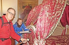 Vom Parade-Bett wirbelt Ulrike Unger mit einem Blasebalg den Staub auf, Restaurator Markus Freitag fängt  ihn dann mit dem Staubsauger auf, in dem sich ein Filter befindet, so dass der Staub nicht wieder mit der Luft nach draußen entweichen kann.