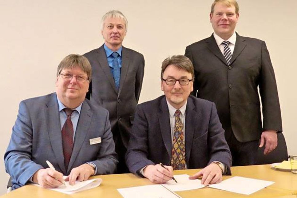 Die Kugelschreiber sind zur Besiegelung des Kooperationsvertrages gezückt. Berufsschulleiter Carsten Ingwertsen-Martensen (l.) und FH-Dekan Prof. Dr. Martin Ryschka. – Dahinter (v.l.): Prof. Dr.-Ing. Helmut Bergmann (Studiengangsleiter an der FH) und Mathias Knorn, Lehrkraft für Elektrotechnik an der KBS.