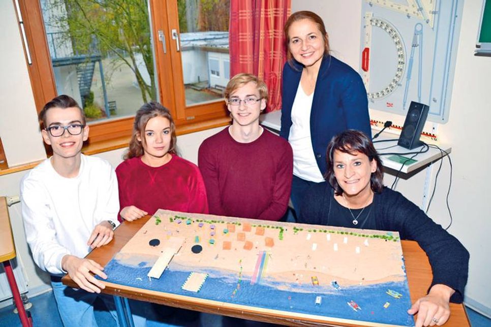 Die Schüler Maximilian Bregovac (vo. v. li.), Lilian Bartsch und Colin Busch mit Silke Szymoniak, Marketingleiterin der TSNT GmbH und Vertreterin der Kooperationspartner, vor dem Projekt „Strand 4.0“, das von den Schülern mit der Tourismus GmbH entwickelt wurde. Bürgermeisterin Hative Kara (hi.) ist stolz auf das bisher Erreichte. (Foto: René Kleinschmidt)