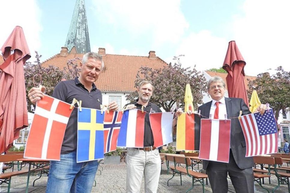 Dieser Anblick dürfte alle Bluesfans freuen. Denn nicht von ungefähr halten Bluesfest-Macher Helge Nickel (Mitte), Hans-Ingo Gerwanski von der Sparkassenstiftung als Sponsor und Marcus Gutzeit als Vorsitzender des Fördervereins für das Eutiner Bluesfest (links) die internationalen Fähnchen hoch: Am morgigen Donnerstag beginnt das 30. Eutiner Bluesfest/BluesBaltica. Dreizehn Acts aus acht Ländern lassen dann bis zum Sonntagabend hören, wie gut es der Stadt tut, auch in diesem Jahr wieder Bühne für dieses Festival-Kleinod zu sein.