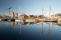 Silke Steen war im klaren Morgenlicht im Neustädter Hafen unterwegs: Während sich Traditionssegler, Baukräne und Speicher im Wasser spiegeln, zeigt sich die Verbindung von maritimer Geschichte und Stadtentwicklung besonders eindrucksvoll.