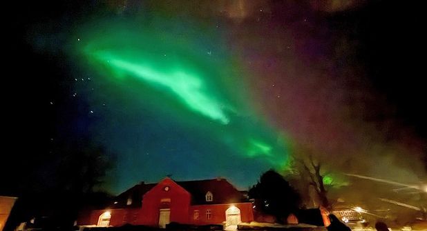 Das Polarlicht zeigt sich über dem Dach der Reithalle des Plöner Herzogs, dem alten „Uhrenhaus“, wie eine leuchtende Rauchfahne.