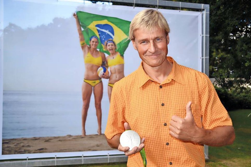 Der Timmendorfer Thomas Nörenberg mit seiner Olympia-Medaille in silber, im Hintergrund die Beach-Volleyball-Goldmädels Ludwig/Walkenhorst. (Foto: René Kleinschmidt)