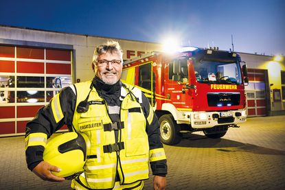 Ein Bild, das eine Geschichte erzählt: Der Gemeindewehrführer im Einsatzlicht vor dem Feuerwehrgerätehaus in Timmendorfer Strand.
