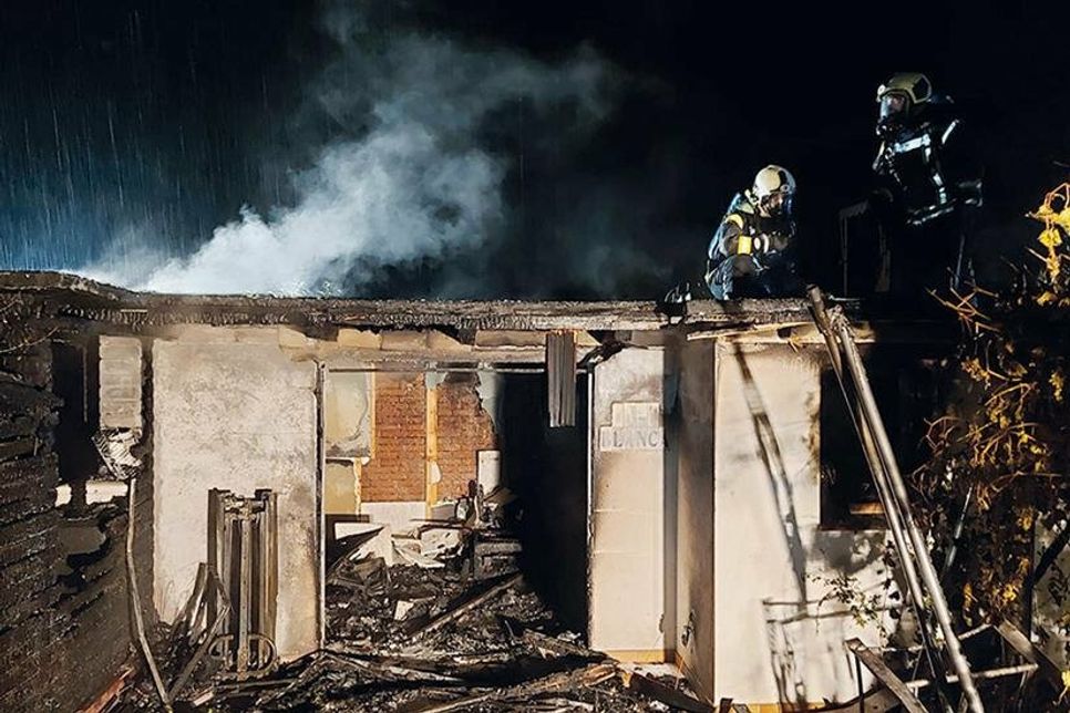 Ein Atemschutztrupp der Freiwilligen Feuerwehren öffnet das Dach des Hauses und sucht nach Glutnestern.