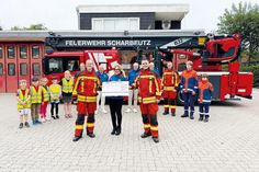 Carolin Dreismann, Präsidentin des Lions Club Lübecker Bucht, überreicht einen Scheck in Höhe von 4.000 Euro an Bo Anderson (vorne rechts) und David Siegmund für die Kinder- und Jugendfeuerwehr Scharbeutz.