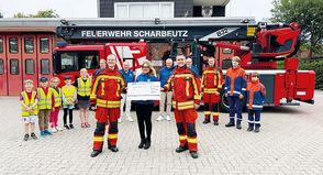 Carolin Dreismann, Präsidentin des Lions Club Lübecker Bucht, überreicht einen Scheck in Höhe von 4.000 Euro an Bo Anderson (vorne rechts) und David Siegmund für die Kinder- und Jugendfeuerwehr Scharbeutz.