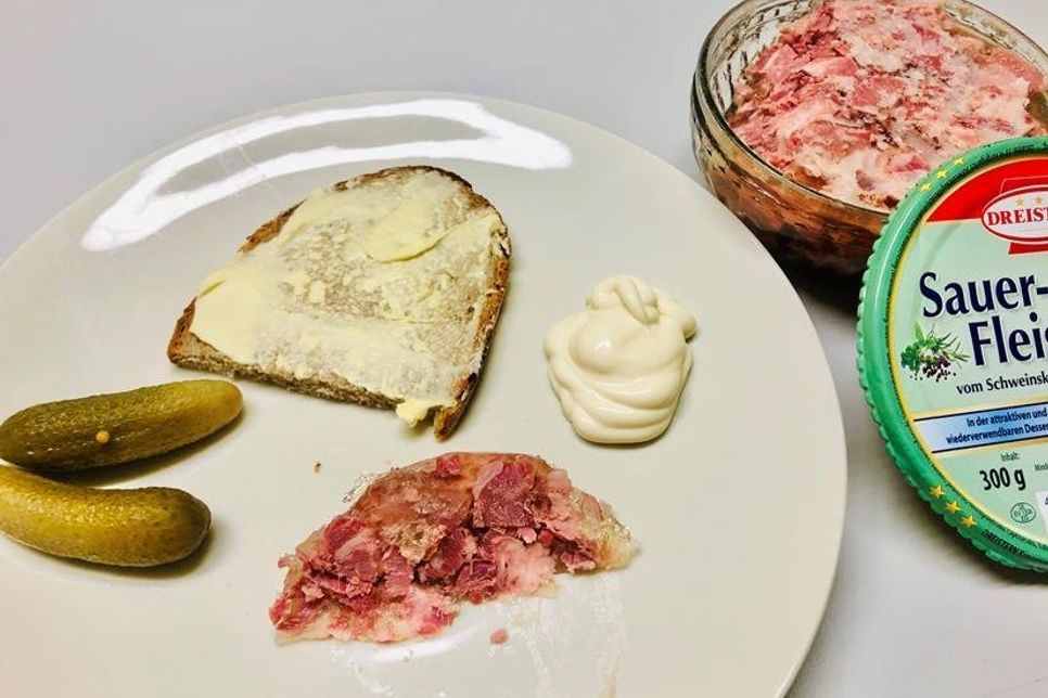 Holsteiner Sauerfleisch mit gebuttertem Brot, sauren Gurken und Remoulade oder Mayonaise.