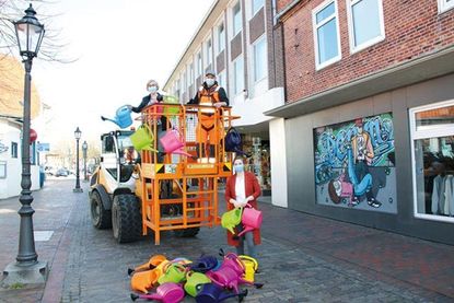 Sabine Bockwoldt, auf dem Hubwagen mit Philip Möller von den Kommunalen Diensten Oldenburg, und Cora Brockmann legen beim Aufhängen der Gießkannen Hand an.