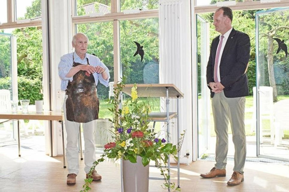Holzpantoffel und eine über 100 Jahre alte Arbeitsschürze: passend zum Anlass hatte Holzschuhmachermeister Lorenz Hamann (li.) während der Preisvergabe seine Arbeitskleidung angelegt