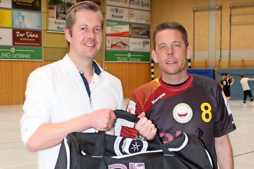 Sören Kühlem, als Vertreter von Ahrens-Immobilien, übergibt „2 The Top“-Trainer Sven Kieckhäfer symbolisch eine der Sporttaschen, mit den die ganze Mannschaft ausgestattet wurde.