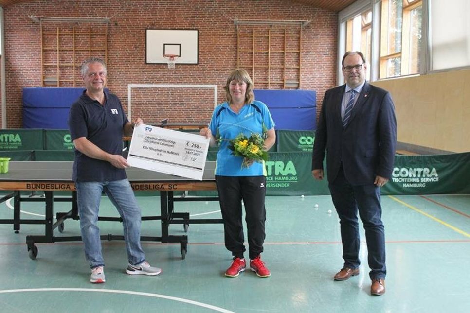 Michael Poske (VR Bank Ostholstein Nord - Plön eG, lks.) und Bürgermeister Mirko Spieckermann bei der Scheckübergabe an Christiane Lehmann vom ESV.