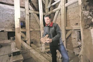 Pastor Friedemann Holmer zeigt ein Stück morsch gewordenes Holz, das von einem Balken stammt.