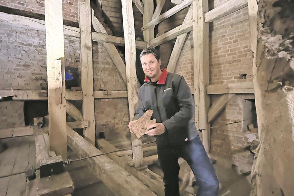Pastor Friedemann Holmer zeigt ein Stück morsch gewordenes Holz, das von einem Balken stammt.