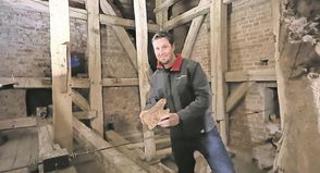 Pastor Friedemann Holmer zeigt ein Stück morsch gewordenes Holz, das von einem Balken stammt.