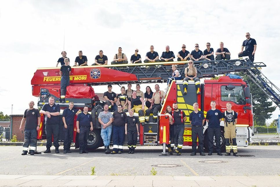 Gruppenfoto mit allen Beteiligten auf und vor der Drehleiter.