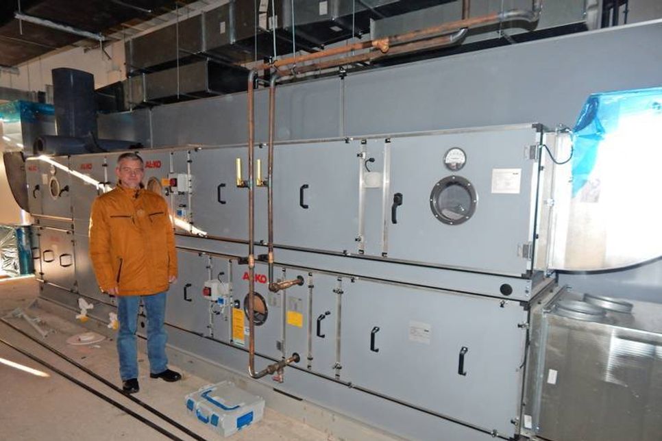 Warenhausleiter Holler vor der Heizungs- und Lüftungsanlage