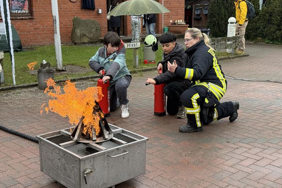 Zwei Tapfere zeigten am Brandsimulator keine Scheu vor den Flammen – an ihrer Seite: Ronja Petersen von der Feuerwehr Sierhagen, Brandschutzerzieherin für Amt und Gemeinde.