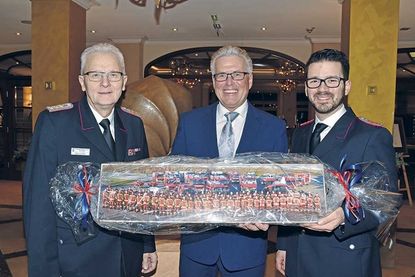 Ein besonderes Geschenk der Feuerwehren der Gemeinde: Reinhold Mang (links) und Patrick Bönig überreichten Volker Owerien ein gerahmtes Foto mit allen jemals von ihm in Dienst gestellten Feuerwehrfahrzeugen.