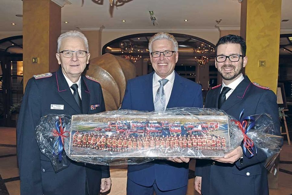 Ein besonderes Geschenk der Feuerwehren der Gemeinde: Reinhold Mang (links) und Patrick Bönig überreichten Volker Owerien ein gerahmtes Foto mit allen jemals von ihm in Dienst gestellten Feuerwehrfahrzeugen.