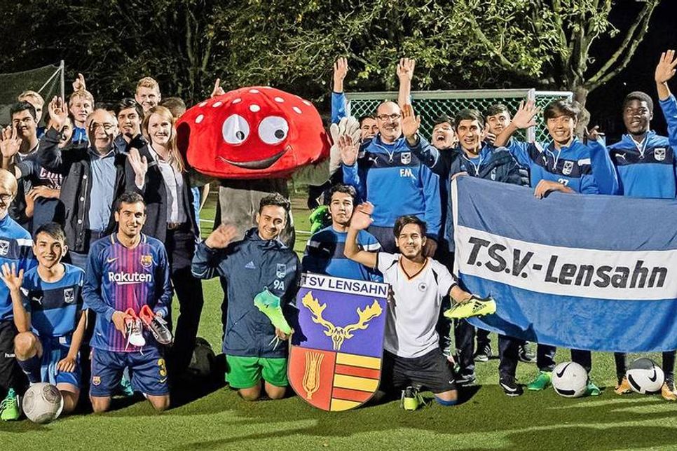 Über 45 neue Fußballschuhe freuen sich neben den jungen Sportlern Sparkassen-Filialleiterin Jasmin Path und Vereinsvorsitzender Wolfgang Prehn (beide links neben Glückspilz „Lotti“) sowie Jugendtrainer Frank Müller (rechts neben Glückspilz „Lotti“).