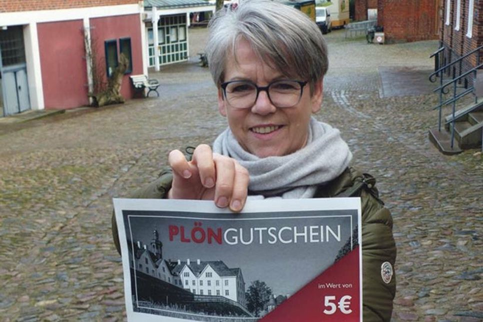 Die Vorsitzende des Stadtmarketing Plön eV Wiebke Kiß zeigt den PlönGutschein im neuen Kleid.