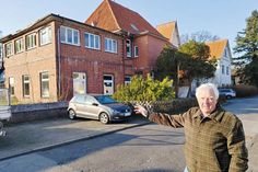 Bauausschuss-Vorsitzender Dieter Boeden zeigt im Barkholtredder auf einen Teil der leerstehenden Gebäuden, die für das neue Wohnprojekt weichen werden.